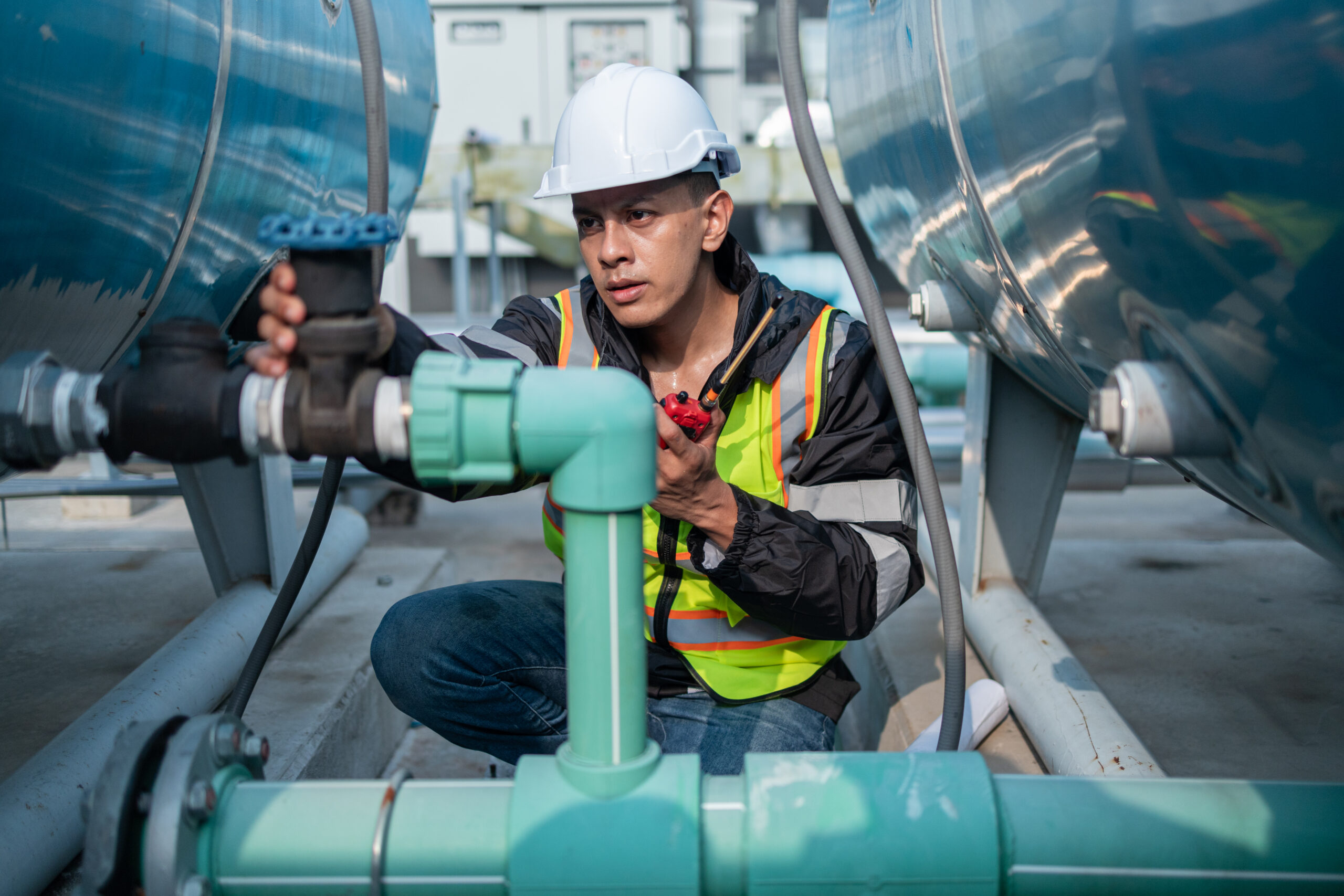 Industrial Engineer Checking Equipment with Tool Focused industrial engineer using a calibration tool to check equipment at a manufacturing plant, ensuring operational efficiency.