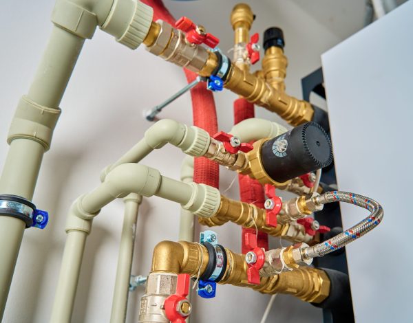 Close-up of heating system featuring plastic pipes, brass fittings, and shut-off valves, ensuring efficient water circulation and temperature control